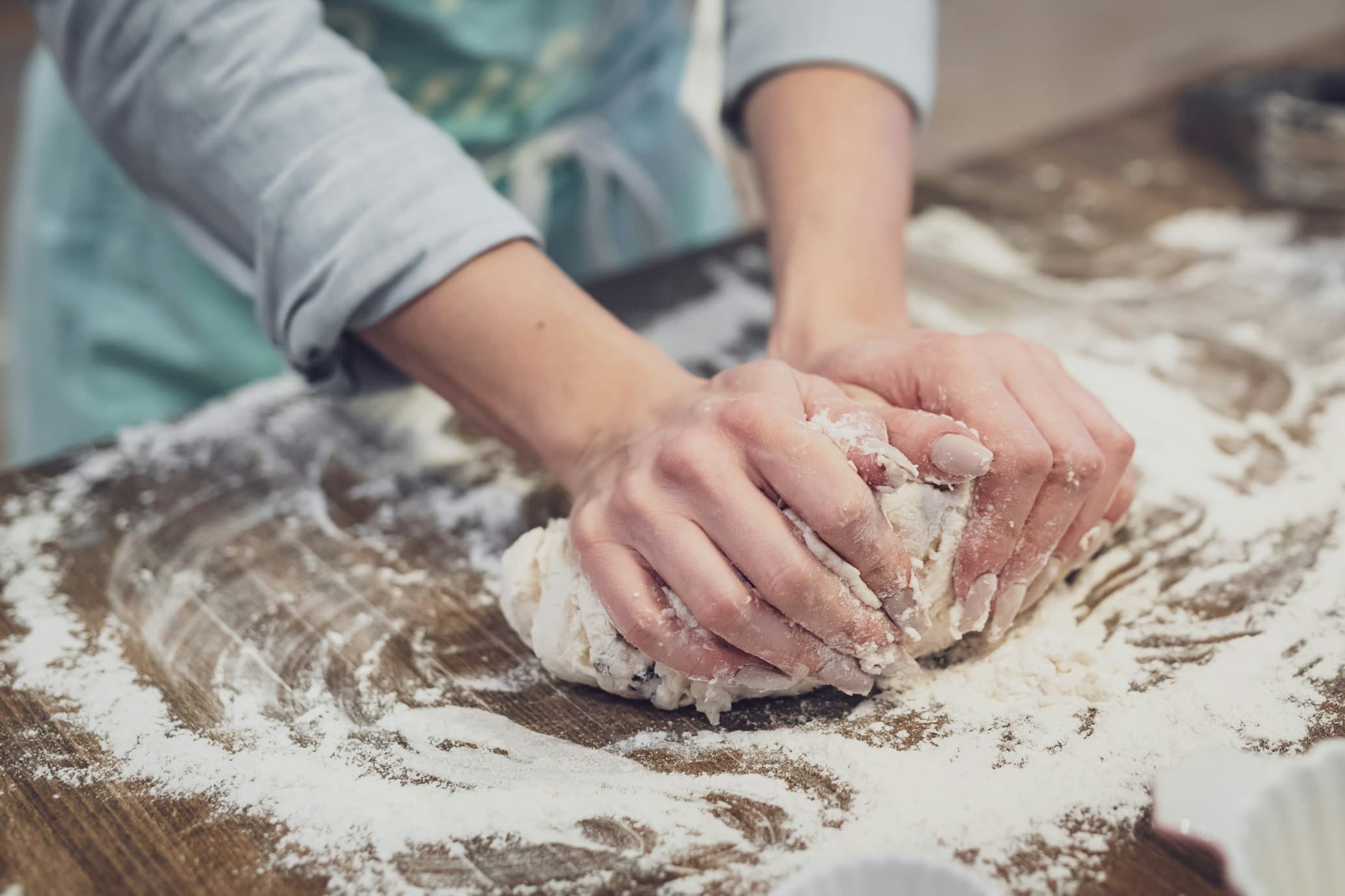 Hands kneading dough on a floured wooden counter