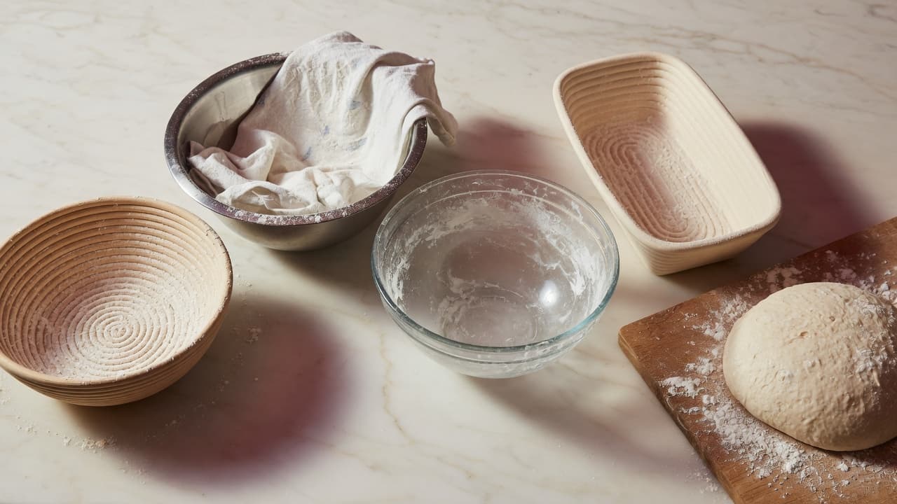 Five sourdough proofing options: rattan banneton, towel-lined bowl, glass bowl, brotform, and free-form dough on a board